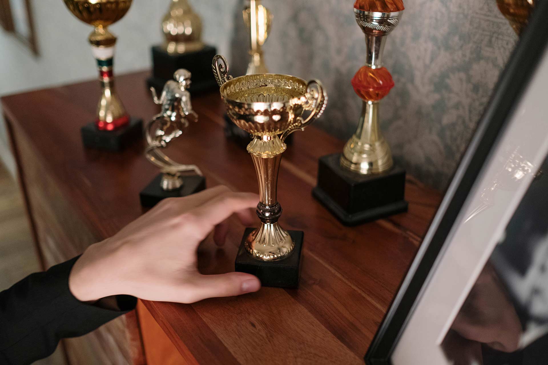 hand putting another trophy on trophy shelf